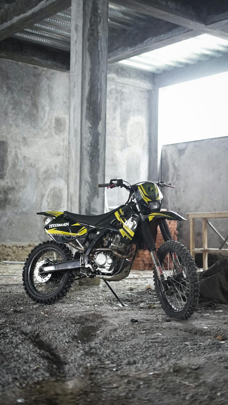 A dirt bike parked inside a concrete industrial building, perfect for adventure enthusiasts.