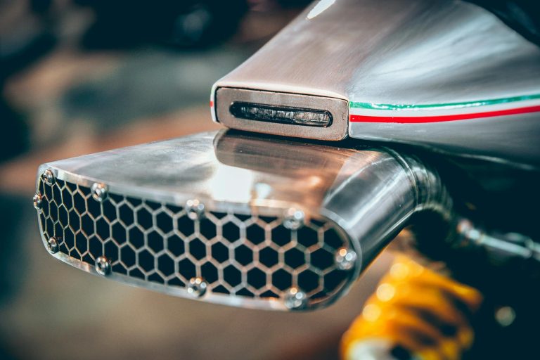Close-up of a modern motorcycle exhaust with an Italian flag strip, showcasing intricate engineering and design.